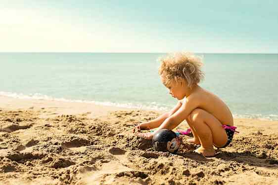 Lapsi leikkimässä hiekkarannalla