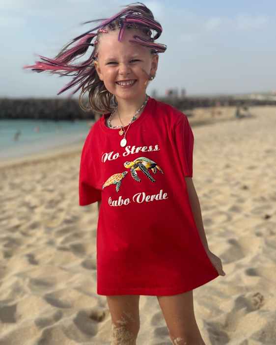 Iloinen pikku lomailija no stress -eiheisessa t-paidassa rannalla