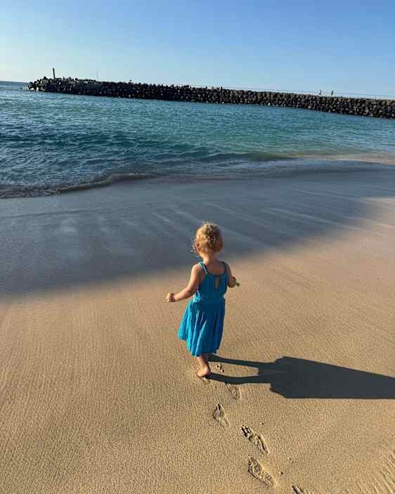 Pikkutyttö kävelee rannalla, vain hänen jalanjälkensä näkyvät