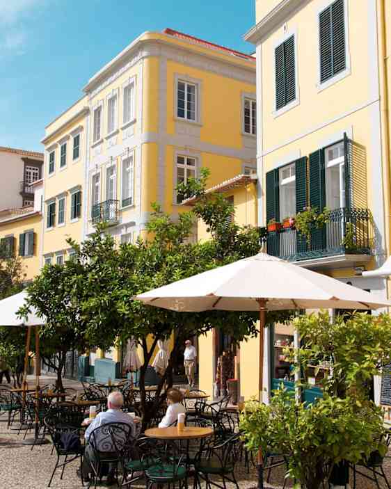 Funchalin katukahvilan terassi kauniin vanhan keltaisen talon vierellä.