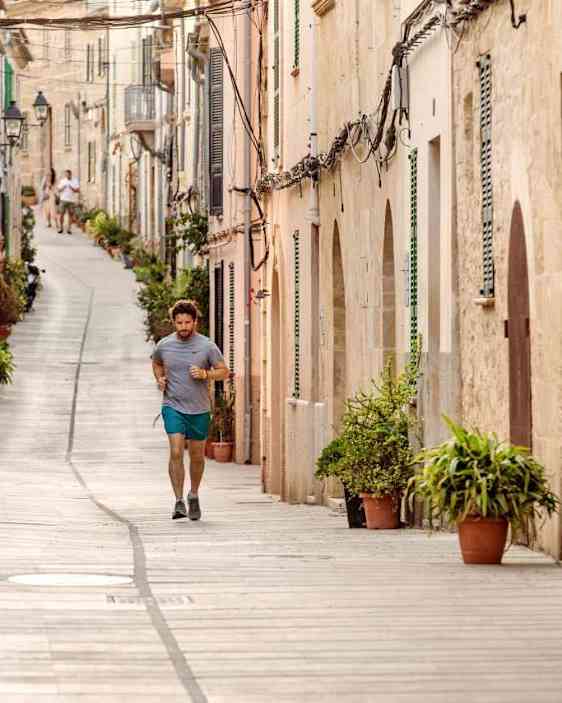 Mies juoksemassa alcudia mukulakivikaduilla