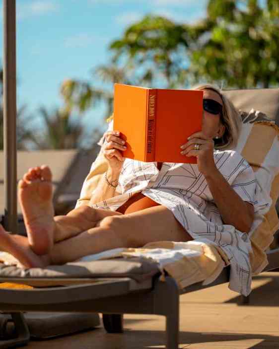 Nainen lukemassa aurinkotuolissa