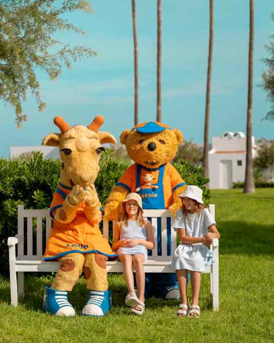 Tytöt istumassa penkillä Lollon kanssa, Bernie seisomassa heidän takanaan.