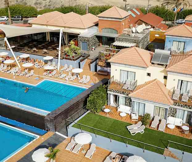 Useita rakennuksia oransseilla katoilla ulkouima-altaan ja aurinkotuolien ympärillä. (Tekoälyn luoma teksti)