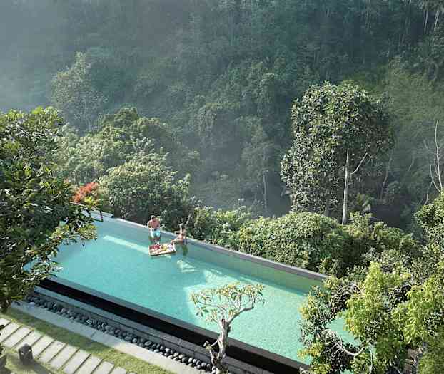 Infinity-allas, josta on näkymä vehreään metsään. Kaksi henkilöä altaassa aamiaistarjottimen kanssa. (Tekoälyn luoma teksti)