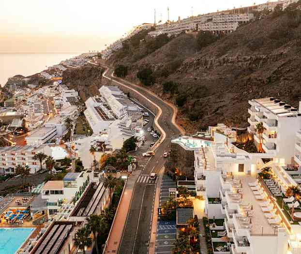 Näkymä hotelleihin ja rinteeseen rannalla, taustalla meri. (Tekoälyn luoma teksti)