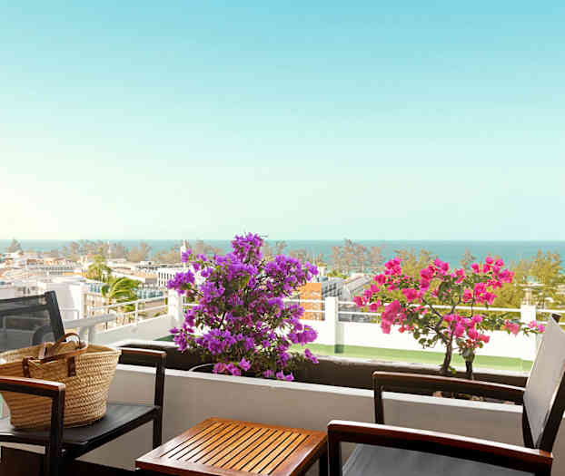 Parveke, jossa pöytä ja tuolit, kukkia ja merinäköala. (Tekoälyn luoma teksti)