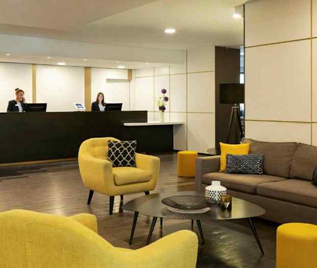 Hotellin aula, jossa on sohvia ja nojatuoleja sekä vastaanottoalue. (Tekoälyn luoma teksti)