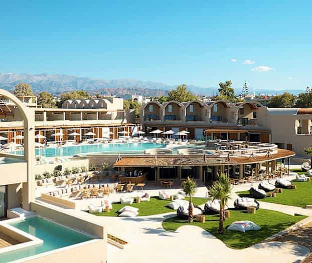 Moderni hotelli, jossa on uima-allasalue ja vehreä puutarha, sekä vuoret taustalla. (Tekoälyn luoma teksti)