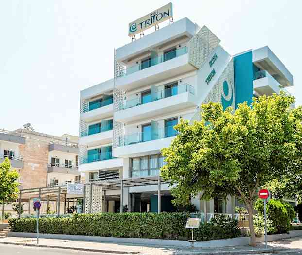 Moderni, viisi kerrosta korkea hotellirakennus parvekkeineen, ympärillä puita. (Tekoälyn luoma teksti)