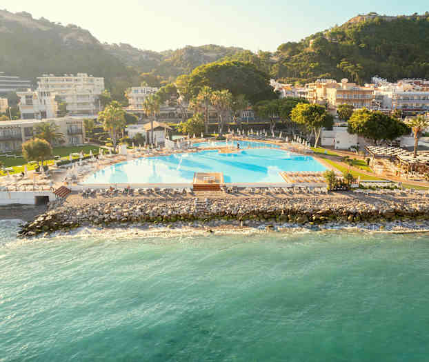 Suuri uima-allas meren äärellä, ympäröity rakennuksilla ja vihreillä alueilla. (Tekoälyn luoma teksti)