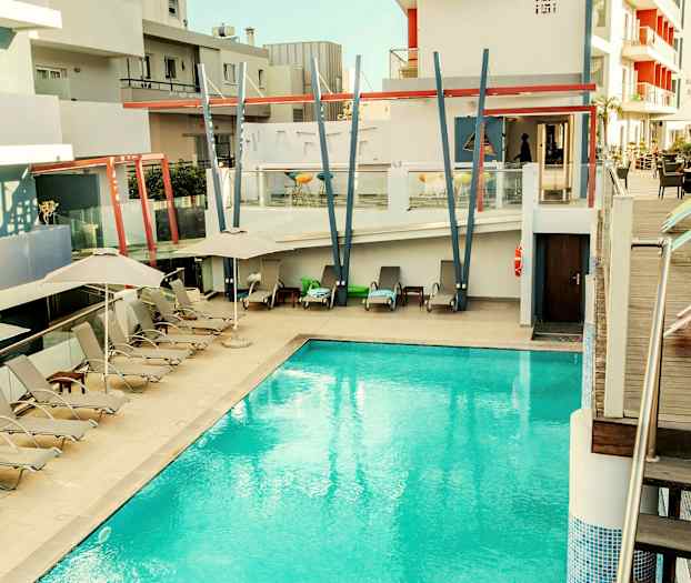 Ulkouima-allas modernissa hotellissa, jossa on aurinkotuoleja ja aurinkovarjoja. (Tekoälyn luoma teksti)