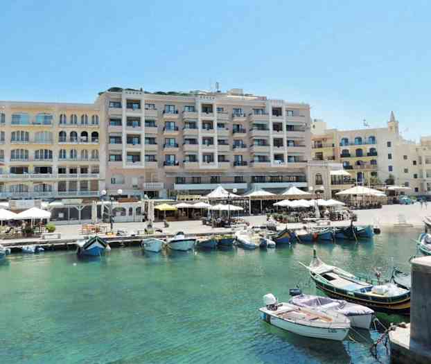 Kuva satamasta, jossa on veneitä kirkkaassa vedessä rakennusten edessä, joissa on ulkoterasseja ja terasseja. (Tekoälyn luoma teksti)