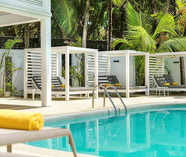 Sininen uima-allas, valkoiset aurinkotuolit ja vihreitä palmuja taustalla. (Tekoälyn luoma teksti)