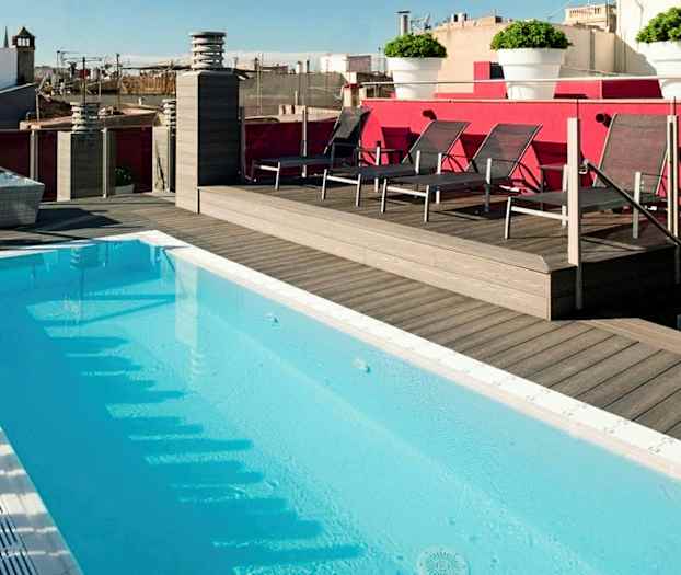 Kattouima-allas, jota ympäröi puuterassi ja aurinkotuoleja, näkymä kaupunkialueelle. (Tekoälyn luoma teksti)