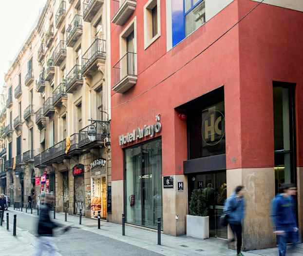 Kaupungin katu, jossa on ihmisiä kävelemässä ohi, rakennusten julkisivuja ja hotellin sisäänkäynti. (Tekoälyn luoma teksti)