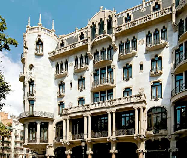 Kuva koristeellisesta rakennuksesta, jossa on koristeellinen julkisivu, parvekkeet ja kaarevat ikkunat. (Tekoälyn luoma teksti)