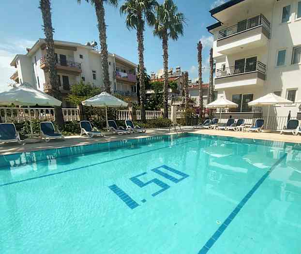 Ulkouima-allas, jota ympäröivät aurinkotuolit ja aurinkovarjot, sekä taustalla näkyy kerrostaloja. (Tekoälyn luoma teksti)