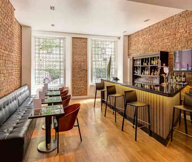 Modernisti suunniteltu baari, jossa on istumapaikkoja ja tiiliseinät. (Tekoälyn luoma teksti)