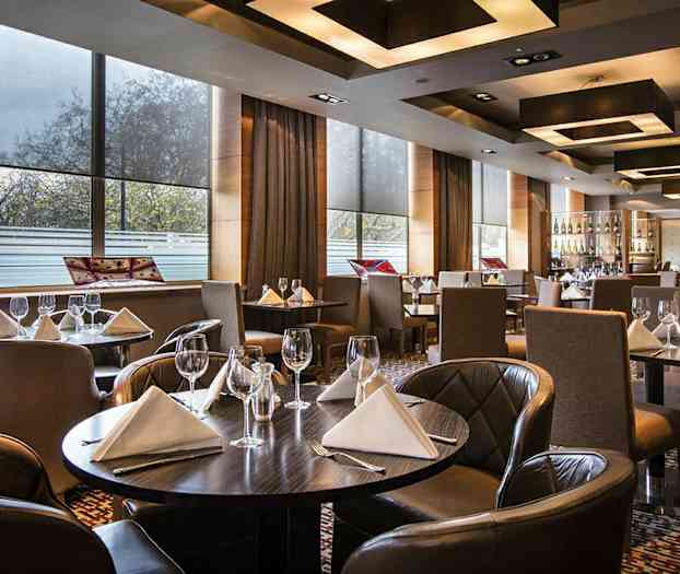 Tyylikäs ravintola, jossa on katettuja pöytiä valkoisin servietein ja viinilasein. (Tekoälyn luoma teksti)