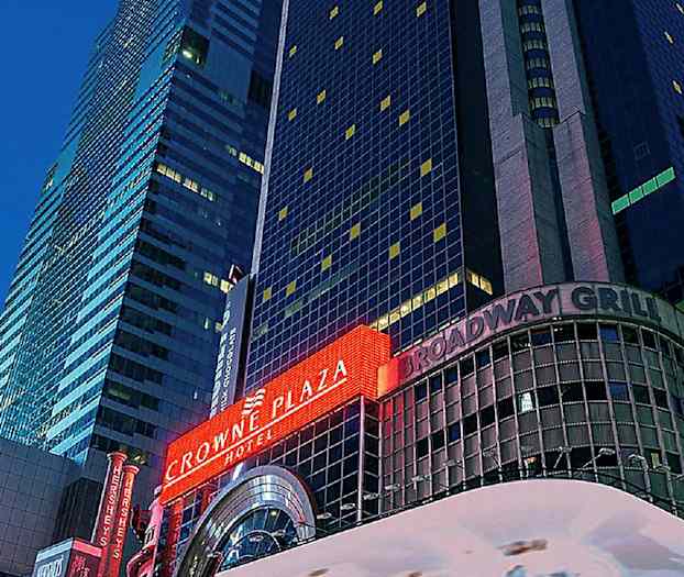 Kuva korkeasta rakennuksesta, jossa on neonkyltit "Crowne Plaza" ja "Broadway Grill". (Tekoälyn luoma teksti)