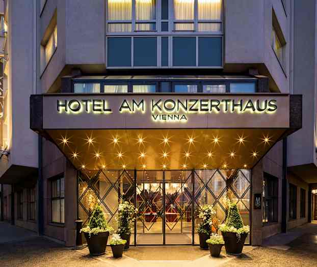 Hotellin sisäänkäynti, jossa on kyltti "Hotel am Konzerthaus Vienna". Valot ja koristeet näkyvät sisäänkäynnin ympärillä ja julkisivussa. (Tekoälyn luoma teksti)