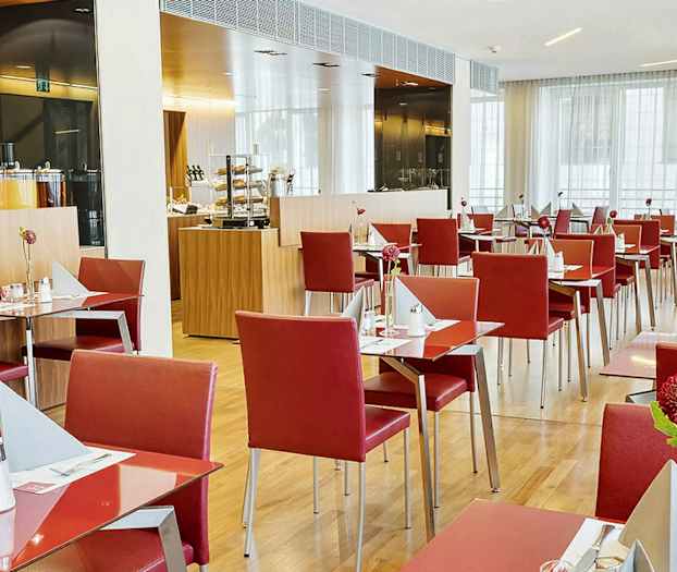 Ravintola, jossa on punaisia tuoleja ja katettuja pöytiä. (Tekoälyn luoma teksti)