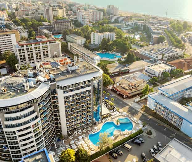 Ilmakuva hotellialueesta, jossa on uima-allas ja ympäröivät rakennukset lähellä merta. (Tekoälyn luoma teksti)