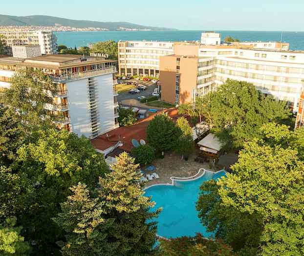 Hotellirakennuksia, uima-allas vehreyden ympäröimänä lähellä merta. (Tekoälyn luoma teksti)