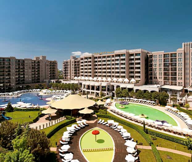 Hotellialue, jossa suuria rakennuksia, uima-altaita ja vihreitä alueita. (Tekoälyn luoma teksti)