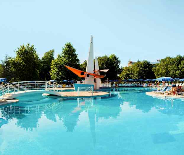 Avoin uima-allas, jossa silta ja koristeellinen vene keskellä, ympärillä aurinkotuoleja ja päivänvarjoja. (Tekoälyn luoma teksti)