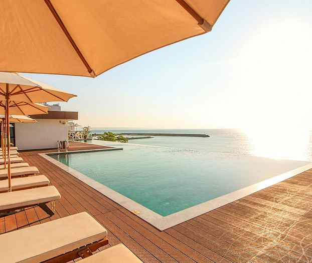 Uima-allasalue aurinkotuoleilla ja aurinkovarjoilla, näkymä merelle. (Tekoälyn luoma teksti)