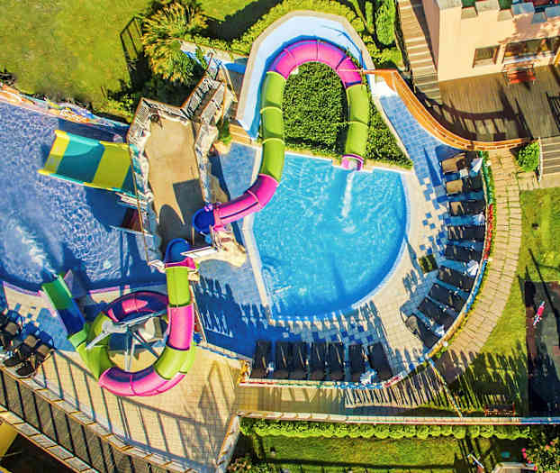 Ilmakuva uima-altaasta liukumäkineen ja aurinkotuoleineen. (Tekoälyn luoma teksti)