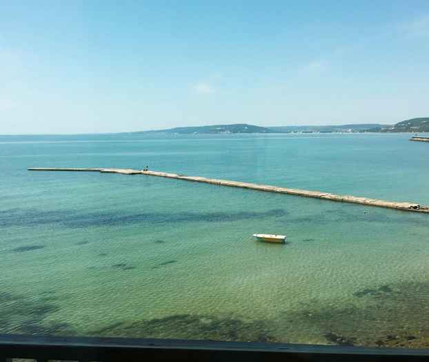 Laituri ulottuu kirkkaaseen siniseen veteen. Yksinäinen vene lepää kiinnitettynä pinnalla. (Tekoälyn luoma teksti)