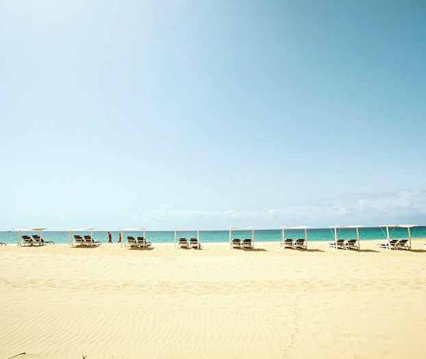 Ranta aurinkotuoleilla ja päivänvarjoilla meren edustalla. (Tekoälyn luoma teksti)