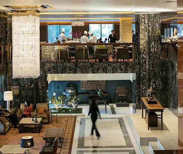 Hotellin aula, jossa on tyylikkäät huonekalut, suuret ikkunat ja suuri kristallikruunu katossa. (Tekoälyn luoma teksti)