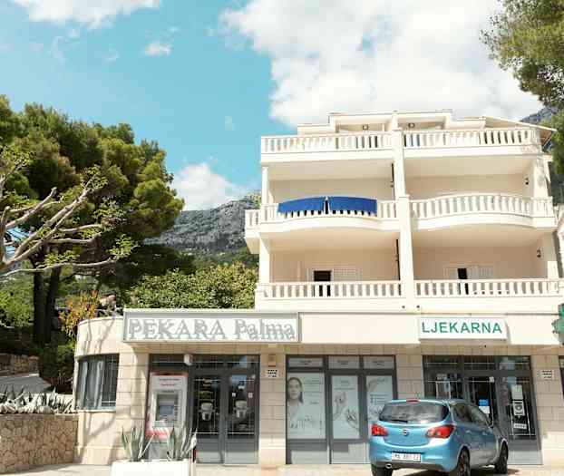 Rakennus, jossa parvekkeita ja kauppoja pohjakerroksessa. (Tekoälyn luoma teksti)