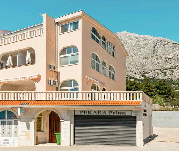 Monikerroksinen rakennus, jossa on parvekkeita. Alemmassa osassa on liiketoimintaa koskevia kylttejä. (Tekoälyn luoma teksti)