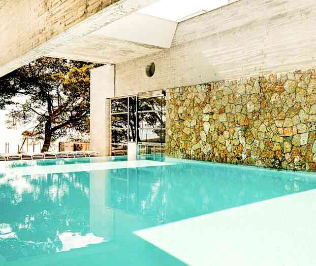 Sisäuima-allas kiviseinällä ja näkymä ulkona oleviin puihin. (Tekoälyn luoma teksti)