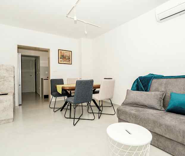 Moderni olohuone, jossa harmaa sohva, ruokapöytä ja tuolit. (Tekoälyn luoma teksti)