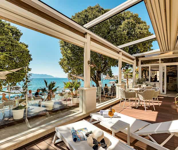 Terassi, jossa on istuimia, aurinkotuoleja ja näkymä merelle. (Tekoälyn luoma teksti)