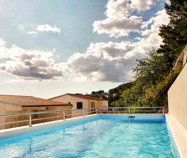 Kuva ulkouima-altaasta, josta on näkymä kattotiilille ja puille pilvisen taivaan alla. (Tekoälyn luoma teksti)