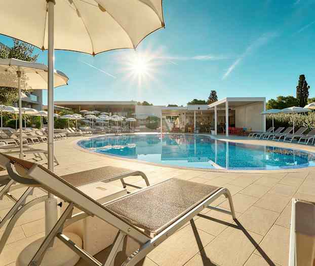 Ulkouima-allas, jota ympäröivät aurinkotuolit ja aurinkovarjot kirkkaan sinisen taivaan alla. (Tekoälyn luoma teksti)