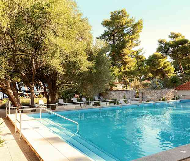 Ulkouima-allas, jota ympäröivät puut ja aurinkotuolit. (Tekoälyn luoma teksti)