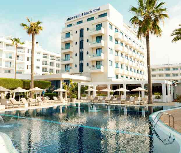 Hotelli, jossa uima-allas, aurinkotuoleja ja aurinkovarjoja etualalla. (Tekoälyn luoma teksti)