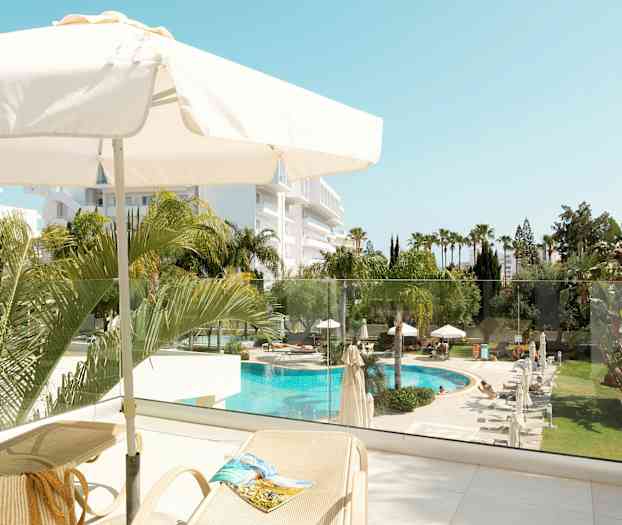 Näköala terassilta, jossa aurinkovarjo, aurinkotuoleja sekä näkymä uima-altaalle ja puutarhaan. (Tekoälyn luoma teksti)