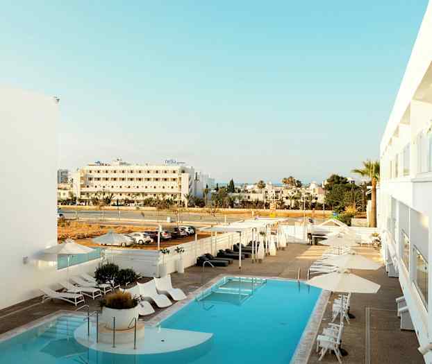 Hotellin uima-allas, jossa aurinkotuoleja ja varjoja, näkymä kadulle ja ympäröiviin rakennuksiin. (Tekoälyn luoma teksti)