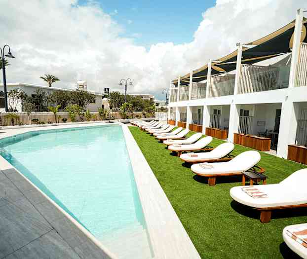 Ulkouima-allas ja aurinkotuoleja hotellirakennuksen vieressä. (Tekoälyn luoma teksti)