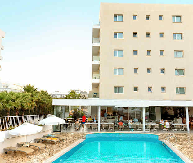 Hotellirakennus ja uima-allas aurinkotuoleineen edessä. Ihmiset istuvat ravintolassa. (Tekoälyn luoma teksti)