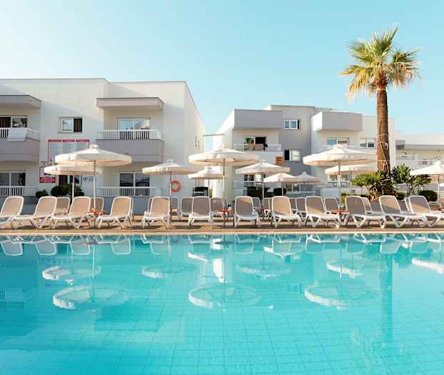 Kuva altaasta, jossa on aurinkotuoleja ja varjoja hotellin edustalla. (Tekoälyn luoma teksti)